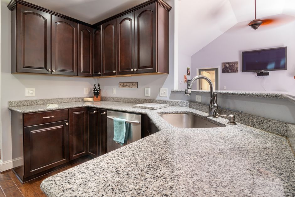 Contemporary kitchen design featuring granite countertops, dark wooden cabinets, and stainless steel appliances.